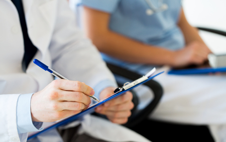 education, profession, people and medicine concept - close up of happy doctors with clipboard at seminar or hospitalの写真素材