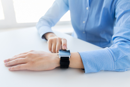 business, technology and people concept - close up of woman hands setting smart watch at officeの写真素材