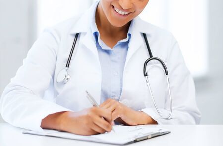 healthcare and medical concept - female doctor with stethoscope writing prescriptionの写真素材