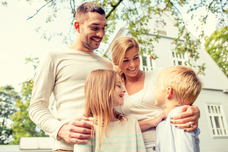 family, happiness, generation, home and people concept - happy family standing in front of house outdoorsの写真素材