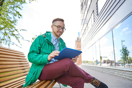 people, style, technology and lifestyle - happy young hipster man with tablet pc computer and fixie bike sitting on bench in cityの写真素材