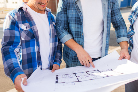 building, construction, development, teamwork and people concept - close up of two smiling builders with blueprint outdoorsの写真素材
