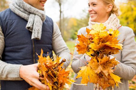 love, relationship, family, season and people concept - close up of happy smiling couple with pile of maple leaves having fun in autumn parkの写真素材