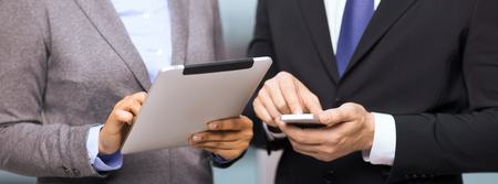 business, technology, internet and office concept - businessman and businesswoman with smartphone and tablet pc computer in officeの写真素材