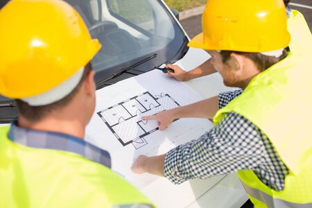 building, construction, development, teamwork and people concept - close up of builders in hardhats...