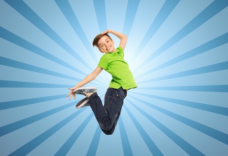 smiling boy jumping in air over blue burst rays background