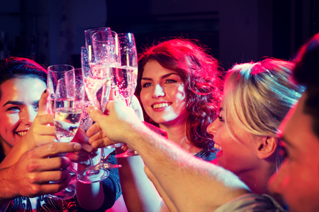 smiling friends with glasses of champagne in clubの写真素材