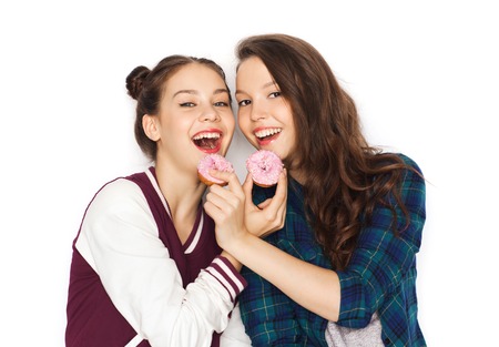 people, friends, teens and friendship concept - happy smiling pretty teenage girls with donuts eating and having funの写真素材