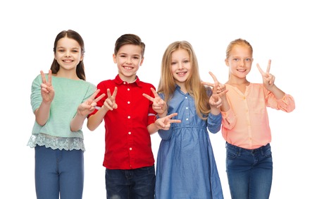 childhood, fashion, friendship and people concept - happy smiling boy and girls showing peace hand signの写真素材