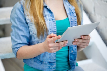 people, technology and internet concept - close up of female hands with tablet pc on stairs