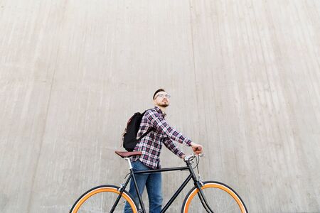 people, travel, tourism, leisure and lifestyle - happy young hipster man with fixed gear bike and backpack on city streetの写真素材
