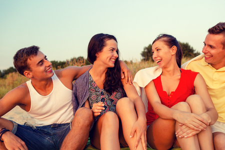friendship, summer vacation, holidays, gesture and people concept - group of smiling friends sitting on beachの写真素材