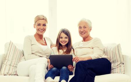 family, generation, technology and people concept - smiling mother, daughter and grandmother with tablet pc computer sitting on couch at homeの写真素材