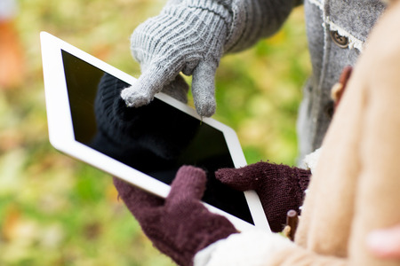 technology, advertisement and people concept - close up of couple hands in autumn gloves holding...