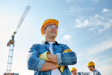 business, building, teamwork and people concept - group of smiling builders in hardhats at construction siteの写真素材
