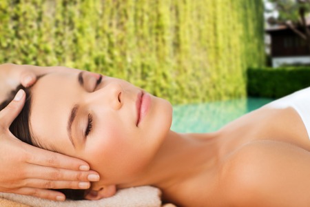 spa, beauty, people and body care concept - beautiful woman getting face treatment over green natural backgroundの写真素材