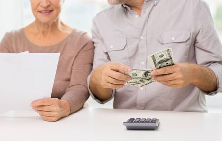 family, business, savings age and people concept - close up of smiling senior couple with bills,...