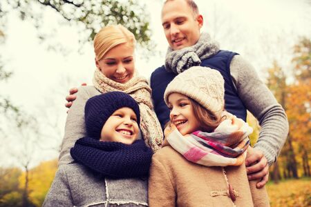 family, childhood, season and people concept - happy family in autumn parkの写真素材
