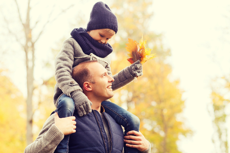 family, childhood, season and people concept - happy father and son having fun in autumn parkの写真素材