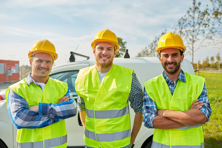industry, building, construction and people concept - happy male builders in high visible vests outdoorsの写真素材