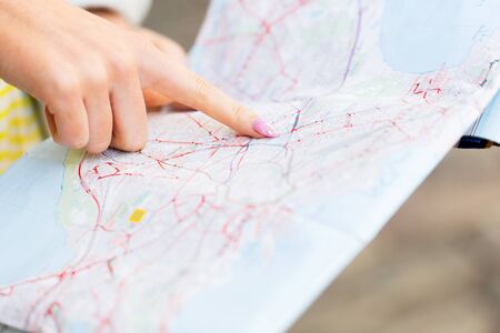 tourism, travel, location and destination concept - close up of woman hand pointing finger to mapの写真素材