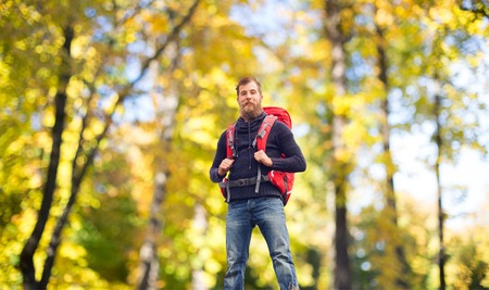 travel, tourism, hike, gesture and people concept - tourist with beard and backpack standing on edge of hill over natural backgroundの写真素材