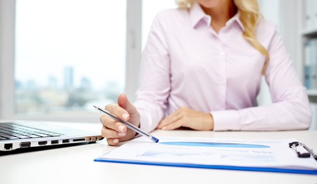 close up of smiling businesswoman with laptop computer and papers sitting in officeの写真素材