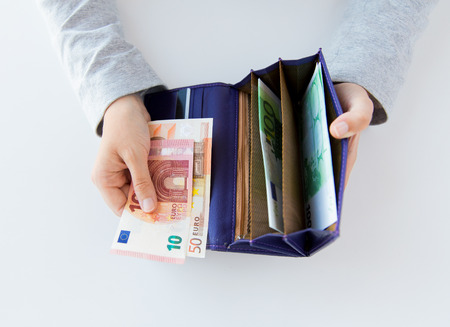 business, finance, saving, banking and people concept - close up of woman hands with wallet and euro...