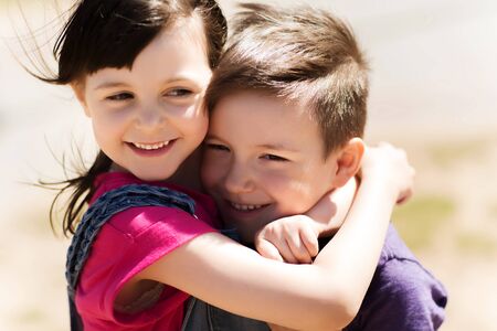summer, childhood, family, friendship and people concept - two happy kids hugging outdoors