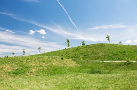nature, season, country and landscape concept - summer green field and hills over blue sky