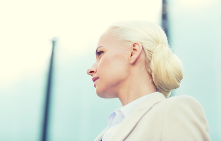 business, people and education concept - young businesswoman over office buildingの写真素材