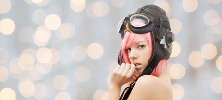 people, sexuality, party and role-playing games concept - pink hair girl in aviator helmet over holidays lights backgroundの写真素材