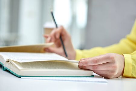 people and education concept - close up of female hands to book or textbook at schoolの写真素材