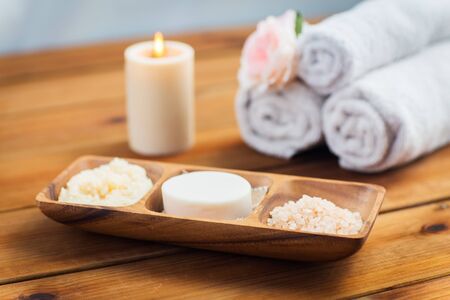 beauty, spa, body care, natural cosmetics and bath concept - close up of soap natural cosmetics  himalayan salt and scrub in wooden bowl on tableの写真素材