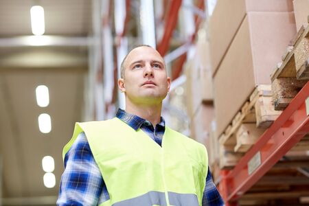 wholesale, logistic, people and export concept - man in reflective safety vest at warehouse
