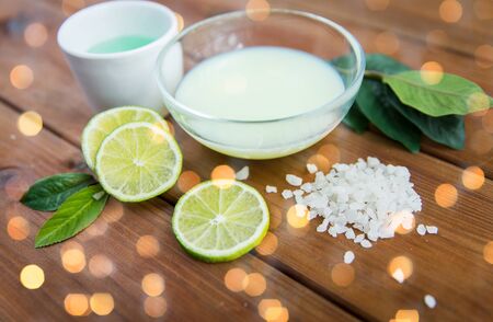 beauty, spa, body care and  natural cosmetics concept - close up of bowls with citrus body lotion, cream and sea salt on wooden tableの写真素材