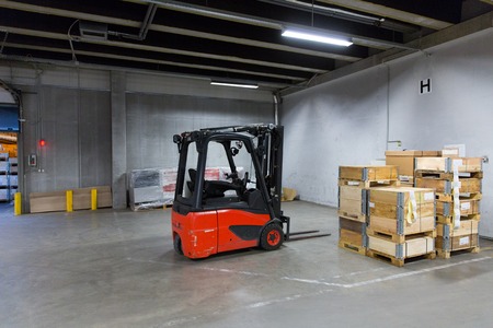 logistic, storage, loading, shipment and equipment concept - forklift loader and boxes at warehouseの写真素材