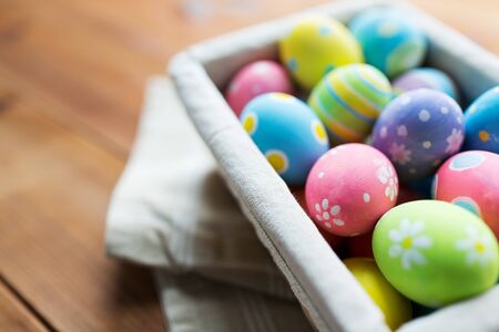 easter, holidays, tradition and object concept - close up of colored easter eggs in basketの写真素材