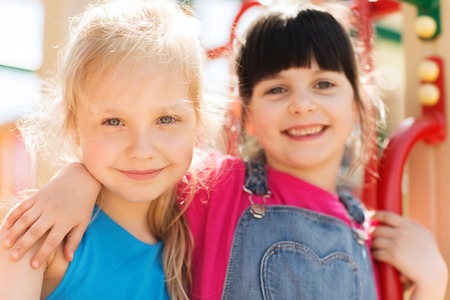 summer, childhood, leisure, friendship and people concept - group of happy little girls on children playground climbing frameの写真素材