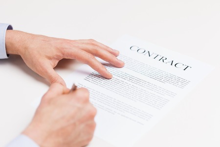 people, business and paperwork concept - close up of male hands signing contract document at office