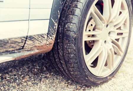 transport, driving and motor vehicle concept - close up of dirty car wheel on groundの写真素材