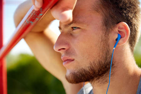 fitness, sport, training and lifestyle concept - young man with earphones listening to music and...