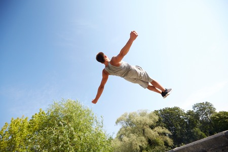 fitness, sport, parkour and people concept - young man jumping in summer parkの写真素材