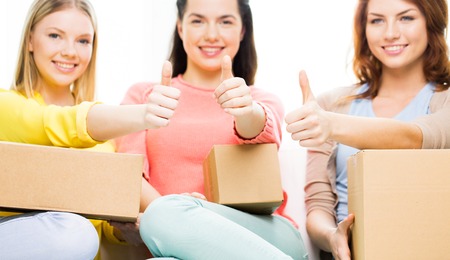transportation, mail, delivery, shipping and people concept - close up of teenage girls with cardboard box at homeの写真素材