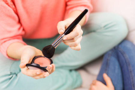 beauty, make up, cosmetics and people concept - close up of woman hands with makeup brush and blushの写真素材