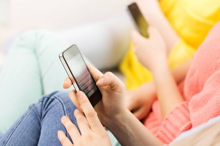 people, technology and leisure concept - close up of hands texting on smartphone at home