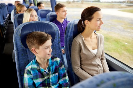 travel, tourism, family, technology and people concept - happy mother and son riding in travel busの写真素材