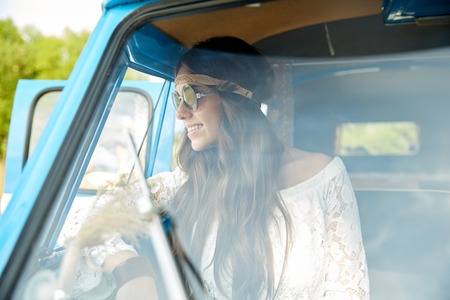 summer holidays, road trip, vacation, travel and people concept - smiling young hippie women in minivan carの写真素材
