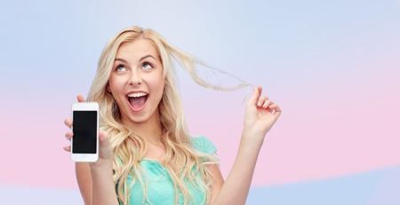 emotions, expressions, technology and people concept - smiling young woman or teenage girl showing blank smartphone screen over pink backgroundの写真素材