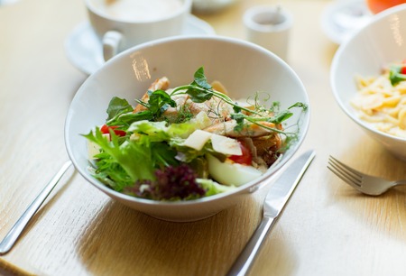 food, cooking and eating concept - close up of caesar salad on plate at restaurant or homeの写真素材